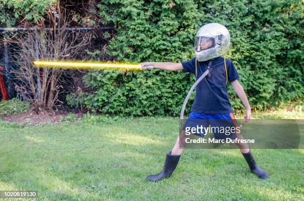 young boy dressed as an astronaut in the backyard during summer day - lightsaber stock pictures, royalty-free photos & images