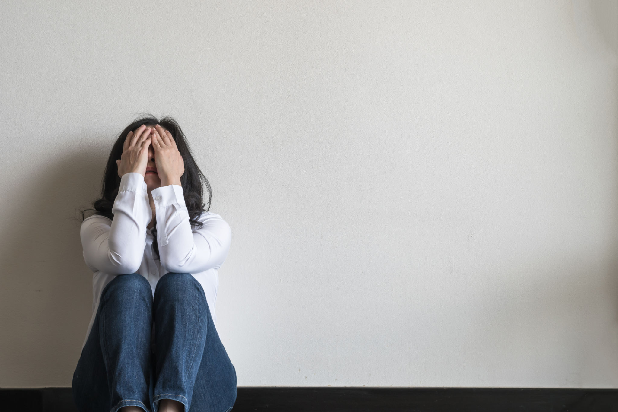 Anxiety disorder menopause woman, stressful depressed emotional person with mental health illness, headache and migraine sitting feeling bad sadly with back against wall on the floor in domestic home Anxiety disorder menopause woman, stressful depressed emotional person with mental health illness, headache and migraine sitting feeling bad sadly with back against wall on the floor in domestic home