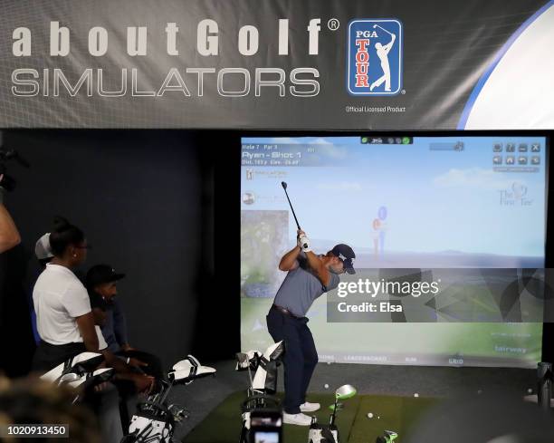 Tour pro Ryan Moore takes his turn at the golf simulator at The First Tee Experience At The Northern Trust at Ridgewood Country Club on August 21,...