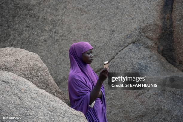 Woman waits for a phone call on the only hill in Pulka that receives cellphone signal on August 1, 2018. - As the presidential race heats up ahead of...