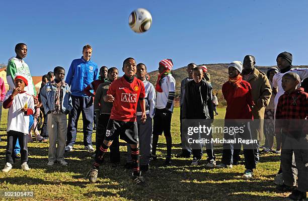 Michael Dawson looks on as Aubrey from the SOS Children's Village plays football during the England players visit on June 15, 2010 in Rustenburg,...