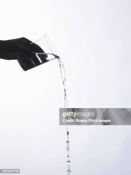 hand holding a glass with a water splash - pouring fotografías e imágenes de stock