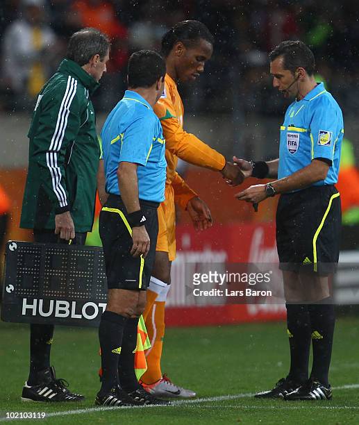 Referee Jorge Larrionda checks the cast under the sleeve of Didier Drogba of the Ivory Coast before he comes onto the pitch as a substitute during...