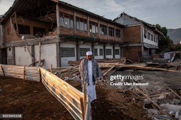 An Indonesian man walks through the ruins of houses as they prepare for Eid al-Adha prayer in Pemenang on August 22, 2018 in Lombok island,...