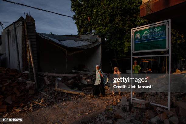 Indonesian Muslims walk through the ruins of houses as they prepare for Eid al-Adha prayer in Pemenang on August 22, 2018 in Lombok island,...