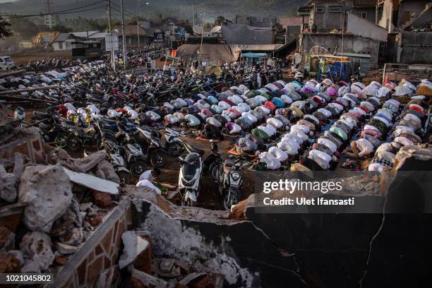 Indonesian Muslims perform Eid al-Adha prayer near the damage houses in Pemenang on August 22, 2018 in Lombok island, Indonesia. Thousands of...