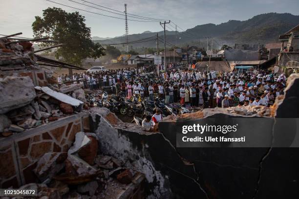 Indonesian Muslims perform Eid al-Adha prayer near the damage houses in Pemenang on August 22, 2018 in Lombok island, Indonesia. Thousands of...