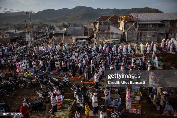 Indonesian Muslims perform Eid al-Adha prayer near the damage houses in Pemenang on August 22, 2018 in Lombok island, Indonesia. Thousands of...