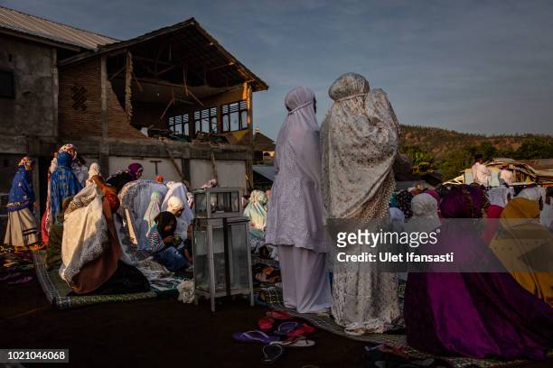 Indonesian Muslims prepare for Eid al-Adha prayer near the damage houses in Pemenang on August 22, 2018 in Lombok island, Indonesia. Thousands of...