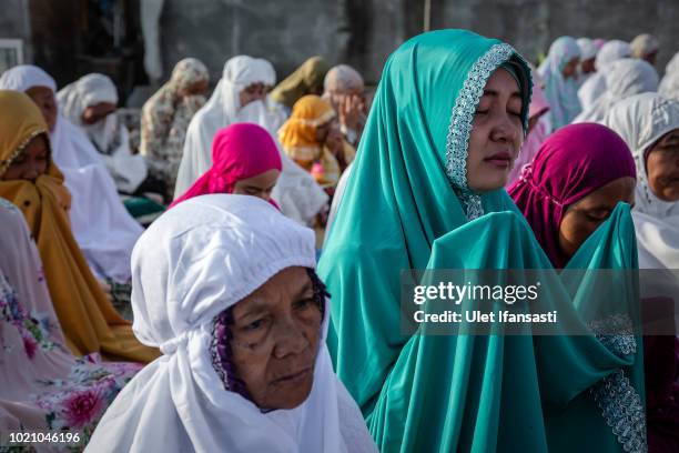 Indonesian Muslims pray after performing Eid al-Adha prayer near the damage houses in Pemenang on August 22, 2018 in Lombok island, Indonesia....