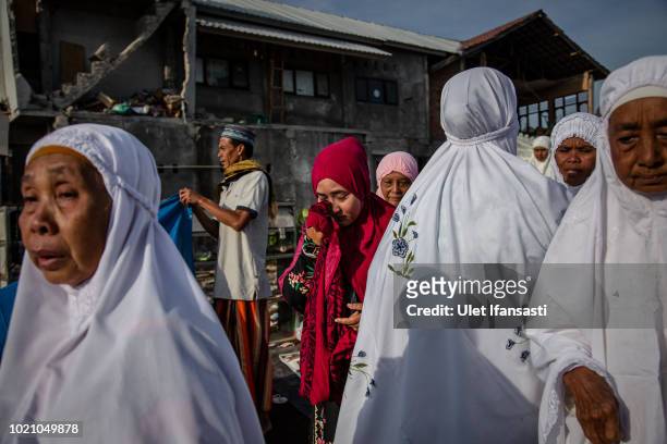 Woman weeps after they perform Eid al-Adha prayer near the damage houses in Pemenang on August 22, 2018 in Lombok island, Indonesia. Thousands of...
