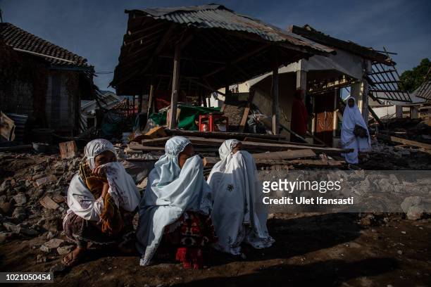 Indonesian muslims women sit near the damage houses after they perform Eid al-Adha prayer in Pemenang on August 22, 2018 in Lombok island, Indonesia....