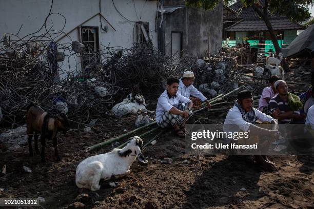 Indonesian muslims sit near the ruins of houses after they perform Eid al-Adha prayer in Pemenang on August 22, 2018 in Lombok island, Indonesia....