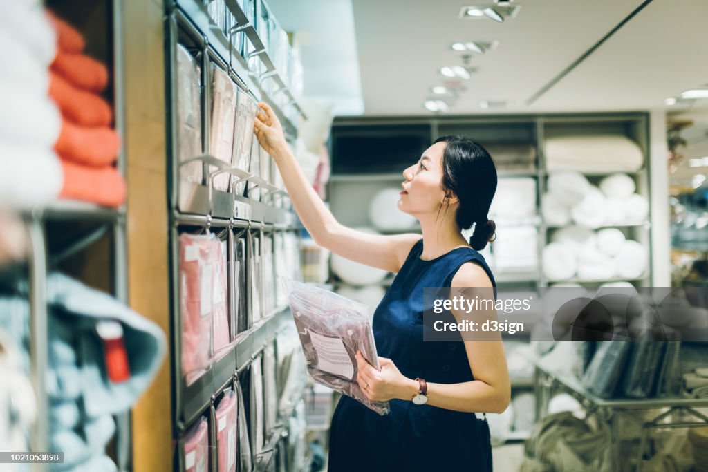 Smiling young pregnant woman shopping for home necessities in shop