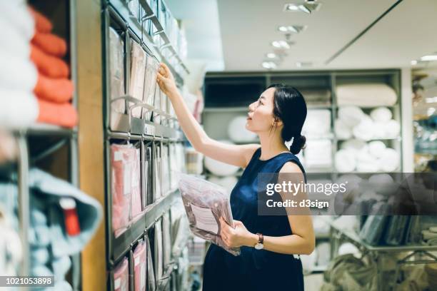 smiling young pregnant woman shopping for home necessities in shop - maternity wear 個照片及圖片檔