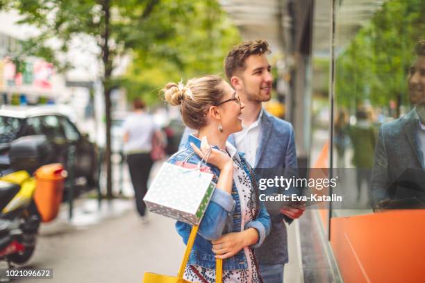 young couple is window shopping downtown city centre - window shopping stock pictures, royalty-free photos & images