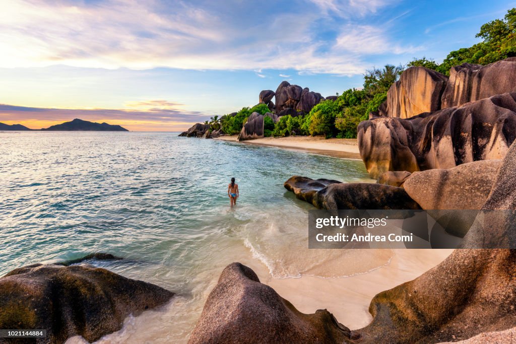 A Tourist walks on Anse Source d'Argent beach at sunset