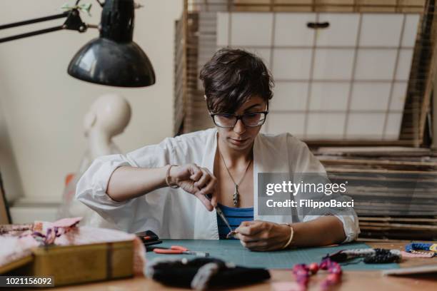 young adult woman working on the creation of some necklaces - bijuteria imagens e fotografias de stock