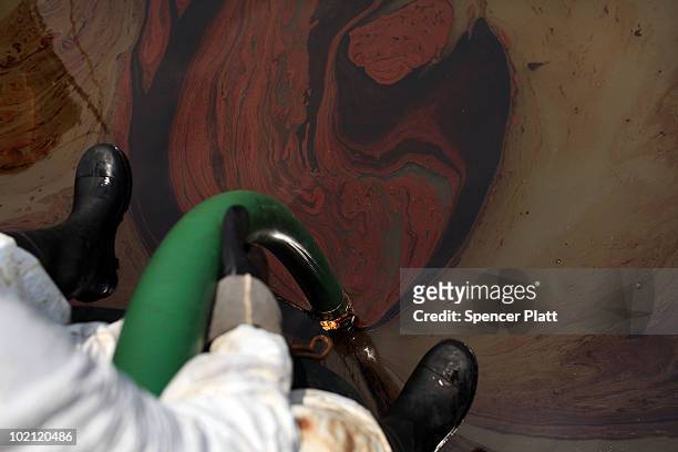 Contract clean-up worker uses a hose to collect oil in Bay Jimmy on June 15, 2010 off of Grand Isle, Louisiana. The BP spill has been called the...