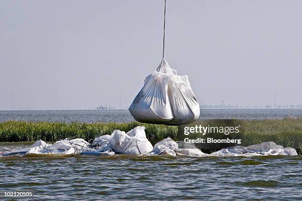 Pound bag of sand is lowered to build a barrier against oil from reaching marshlands off the coast of Venice, Louisiana, U.S., on Tuesday, June 15,...