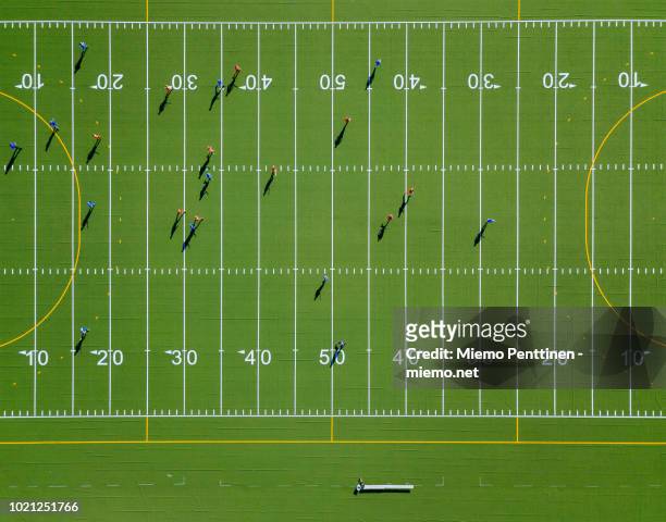 top-down aerial view onto a green american football field with players - campo de fútbol americano fotografías e imágenes de stock
