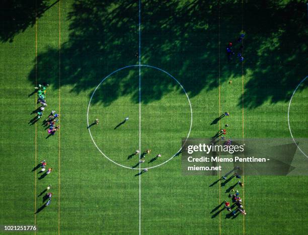 top-down aerial view onto a green soccer field with players gathering - aerial view of football field stock pictures, royalty-free photos & images