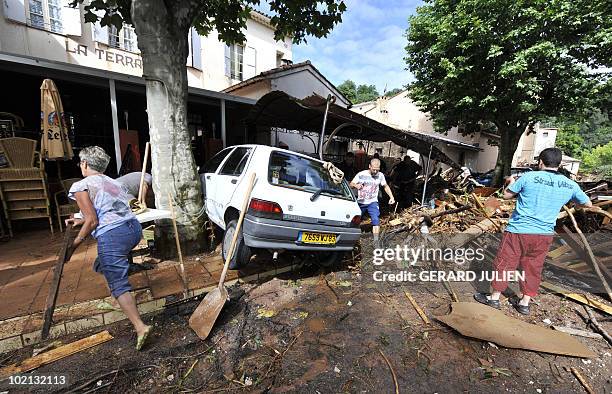 People clean in the aftermath of flooding in a western district of the French south eastern city of Les Arcs sur Argens on June 16, 2010. At least...