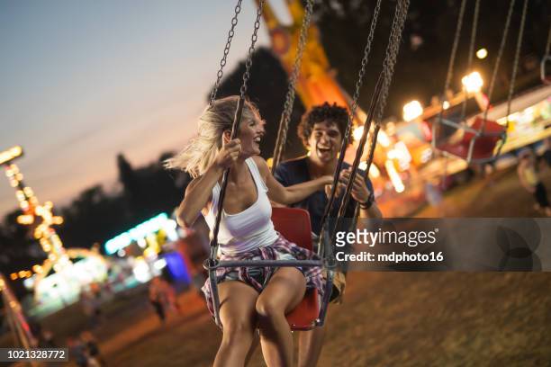 happy young couple on carousel in amusement park - oktoberfest 2018 stock pictures, royalty-free photos & images