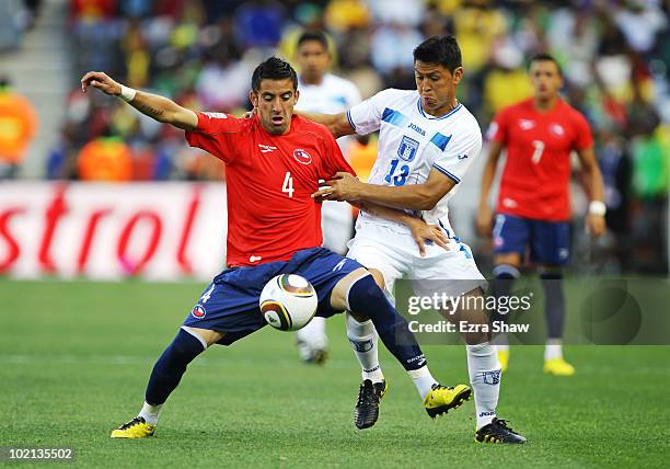 Roger Espinoza of Honduras tackles through the legs of Mauricio Isla of Chile during the 2010 FIFA World Cup South Africa Group H match between...