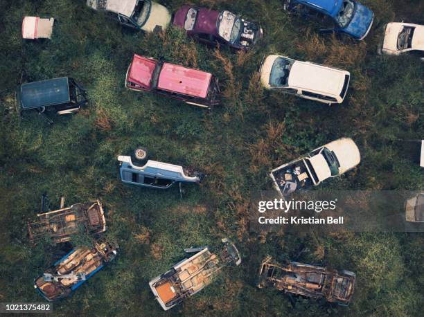 wrecked and abandoned car scrap yard in overgrown vegetation birds eye view - abandoned car - fotografias e filmes do acervo