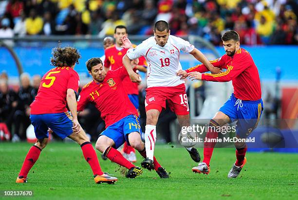 Eren Derdiyok of Switzerland is challenged by Carles Puyol, Xabi Alonso and Gerard Pique of Spain during the 2010 FIFA World Cup South Africa Group H...