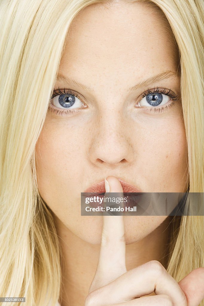 Young woman with finger on lips, close-up