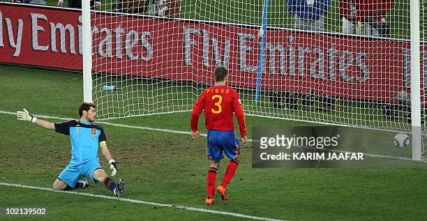 Spain's goalkeeper Iker Casillas land Spain's defender Gerard Pique look as the ball touches the goal during their Group H first round 2010 World Cup...