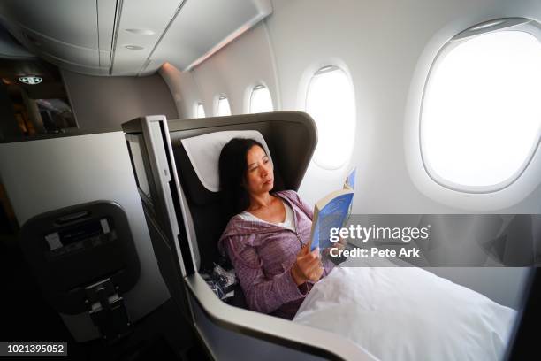 enjoying first class with a book - flying reading stock-fotos und bilder