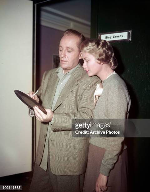 American singer and actor Bing Crosby signs one of his records for actress Grace Kelly during filming of 'The Country Girl', directed by George...