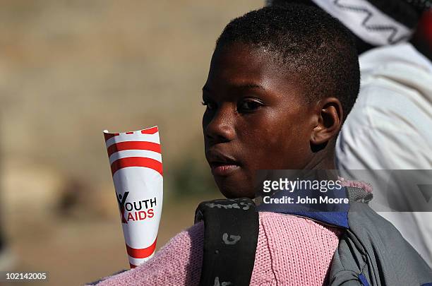 Soweto youth holds HIV/AIDS awareness literature while watching a street soccer match held by the non-profit Population Services International ,...