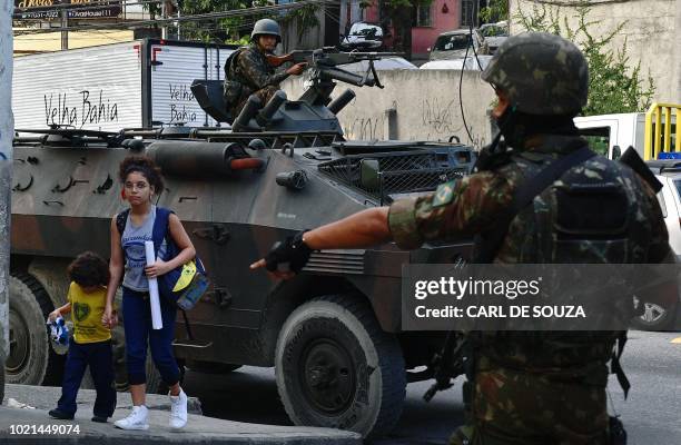Children walk near soldiers at the Complexo do Alemao favela, in Rio de Janeiro, Brazil on August 22, 2018. Rio de Janeiro's drug war hit a bloody...