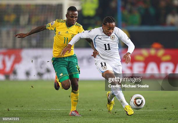 Teko Modise of South Africa and Alvaro Pereira of Uruguay tussle for the ball during the 2010 FIFA World Cup South Africa Group A match between South...