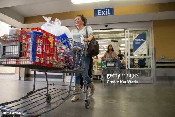 Katya Rivasplata pushes a large cart of supplies including Aloha Water in preparation for Hurricane Lane at Sam's Club on Wednesday, August 22, 2018...
