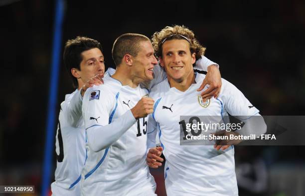 Diego Forlan of Uruguay celebrates after scoring the second goal from the penalty spot with team mates Alvaro Fernandez and Diego Perez during the...