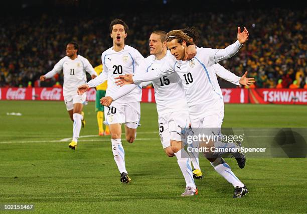 Diego Forlan of Uruguay celebrates after scoring the second goal from the penalty spot with team mates Alvaro Fernandez and Diego Perez during the...