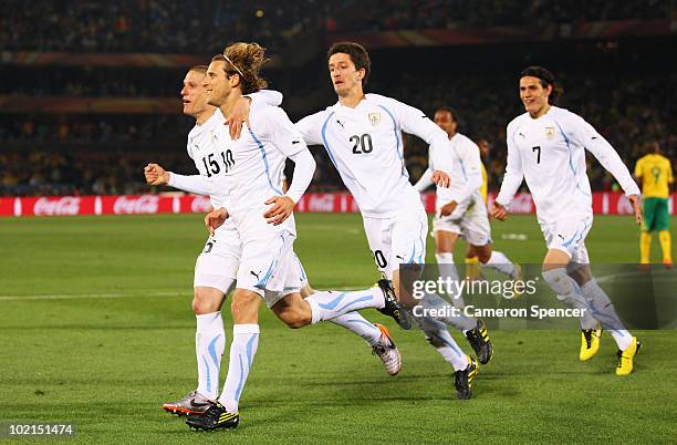 Diego Forlan of Uruguay celebrates after scoring the second goal from the penalty spot with team mates Alvaro Fernandez and Diego Perez during the...