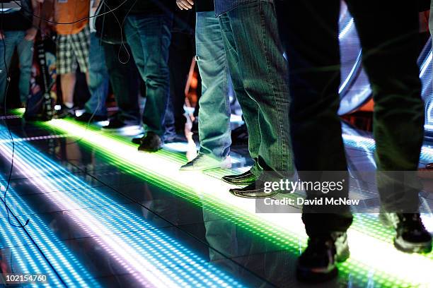 The floor is lit under the feet of people trying out the Disney TRON game at the SIMS exhibit in the annual Electronic Entertainment Expo at the Los...