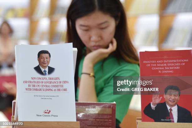 Woman looks at books near a display of books about Chinese President Xi Jinping at the Beijing International Book Fair in Beijing on August 23, 2018....