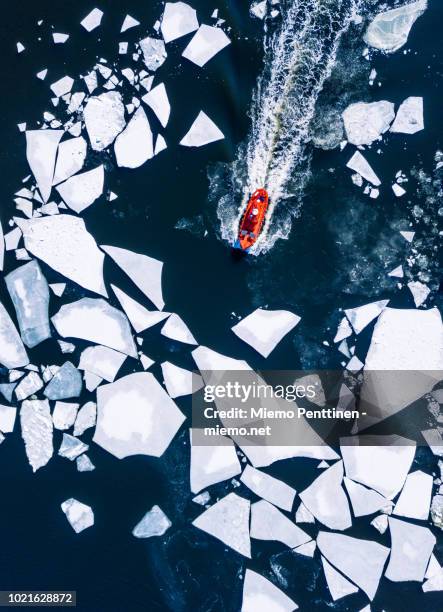 wintery top-down aerial view of red ice-breaker pushing through cracked ice on baltic sea around helsinki - marine marchande photos et images de collection