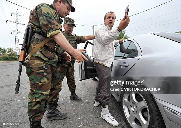 Kyrgyzs special police officer discovers a pistol as he searches a driver at a check point in Osh on June 17, 2010. Deadly inter-ethnic clashes that...