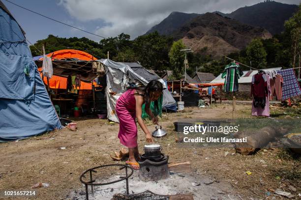 Girl cooks rice at the temporary shelter in Sembalun on August 23, 2018 in Lombok island, Indonesia. Thousands of residents remain stranded at the...