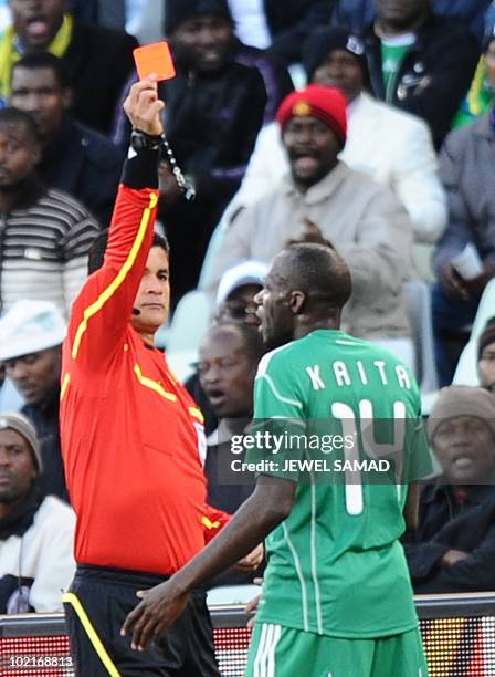 Colombian referee Oscar Ruiz hands a red card to Nigeria's midfielder Sani Kaita after the latter kicked Greece's defender Vasilis Torosidis during...