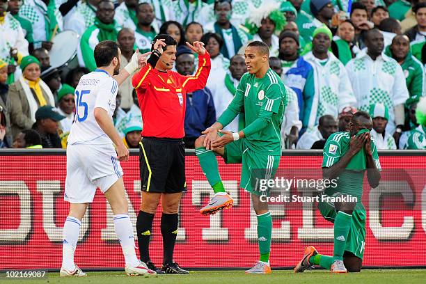 Sani Kaita of Nigeria covers his face after being shown a red card as team mate Peter Odemwingie gestures to Vassilis Torosidis of Greece during the...
