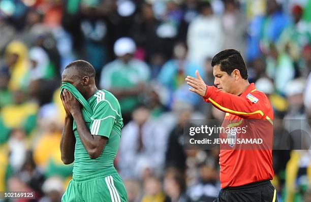 Nigeria's midfielder Sani Kaita hides his face after being handed a red card by Colombian referee Oscar Ruiz for kicking Greece's defender Vasilis...